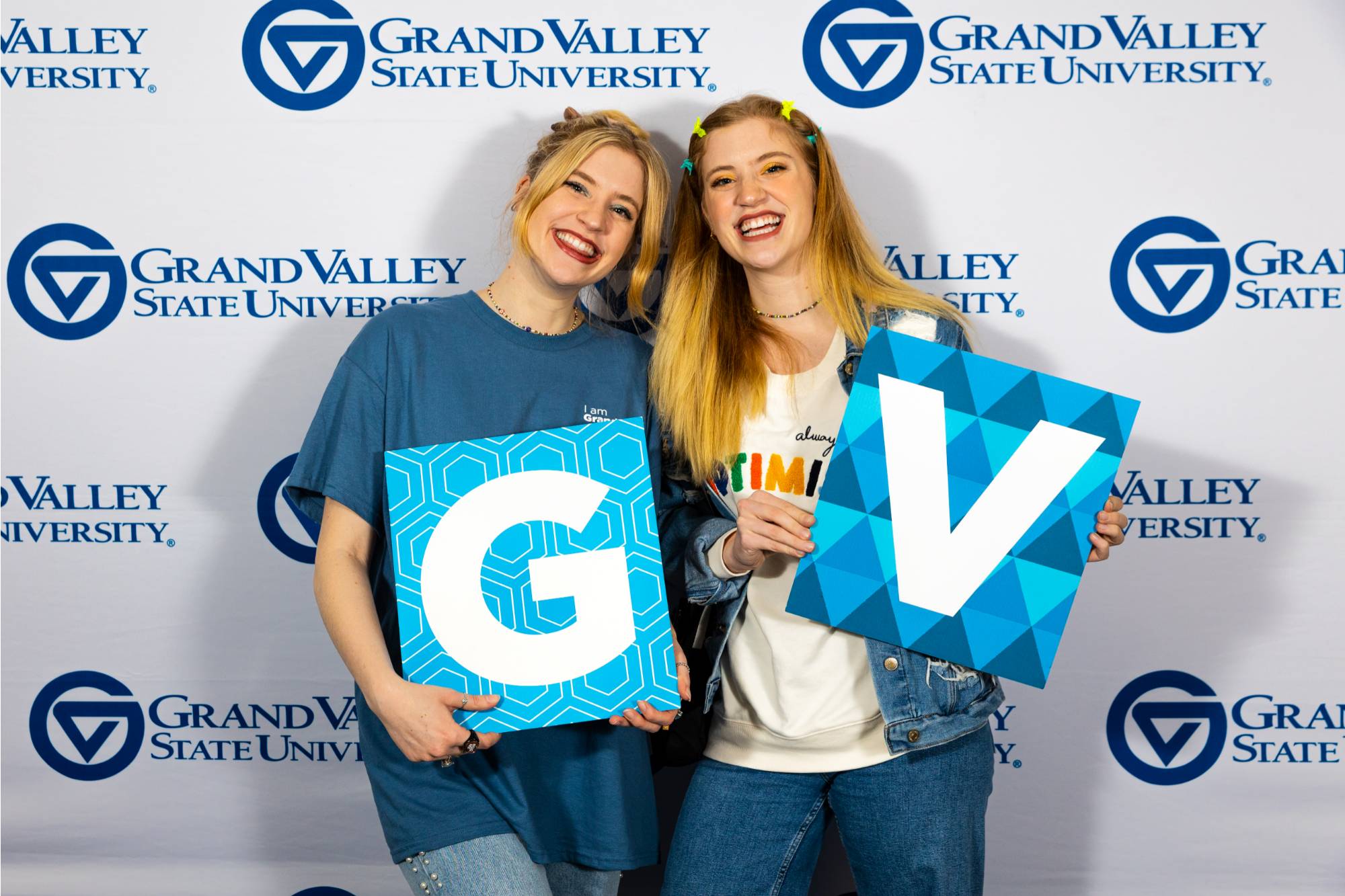 two women hold up their I am Grand Valley certificates.